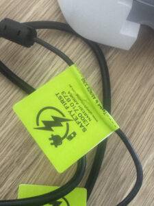 A close-up of a power cord with a bright green "tested and tagged" sticker.