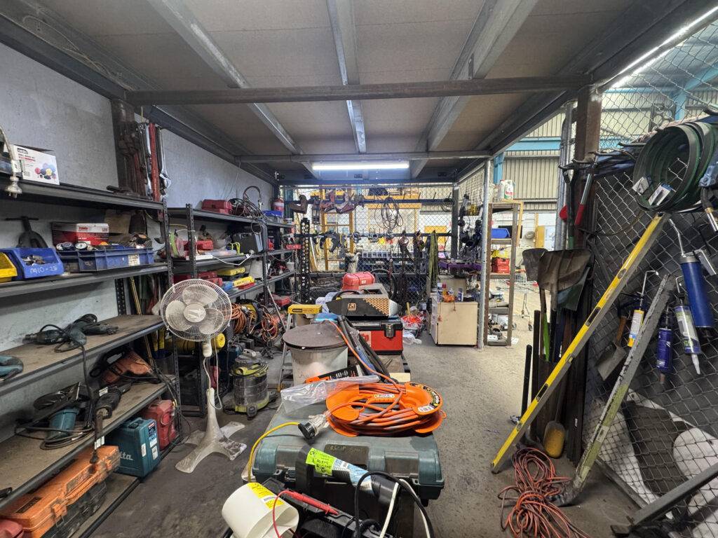 A professional technician performing an electrical test and tag on industrial machinery in a factory, ensuring safety and compliance.